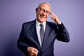 Grey haired senior business man wearing glasses and elegant suit and tie over purple background Smiling pointing to head with one Royalty Free Stock Photo