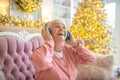 Grey-haired woman listening music in headphones and feeling delighted