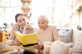 Grey-haired woman reading sitting near caregiver Royalty Free Stock Photo