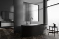 Grey hotel bathroom interior with tub and washbasins, partition and window