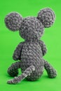 Grey knitted mouse with a heart in hand on a green background, rear view Royalty Free Stock Photo