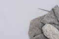 grey knitting yarn in a skein with needles and a scarf