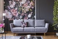 Grey lounge with patterned cushion in real photo of dark living