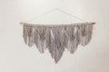 Grey macrame decoration on white wall