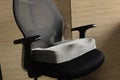 Grey Memory Foam coccyx cushion in black office chair