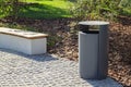grey minimalist dustbin and wooden Park bench with mulched landscape behind