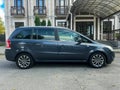 Grey minivan parked in front of an elegant building with intricate architecture, surrounded by Royalty Free Stock Photo