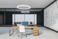 Grey office room with chairs and computer on wooden tables, marble floor