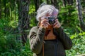 Grey old lady on a photo shoot, with a FED 4, 35mm camera looking through the viewfinder of a retro slr film camera. Royalty Free Stock Photo