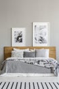 Grey patterned blanket on wooden bed in bedroom interior with po