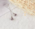 Grey pendant flower earrings in the shape of a flower.Earrings are flanked by cardboard, floral specimens and other ornaments