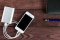 Grey phone and power bank connected by cord with pen and notebook Royalty Free Stock Photo