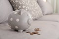 Grey piggy bank and coins on sofa