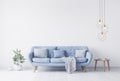 Grey pillow above blue Scandinavian sofa in modern interior. wooden side table with gold elegant accessories. Royalty Free Stock Photo