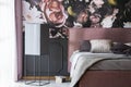 Grey pillows and bedding on bed in pink bedroom interior with flower wallpaper. Real photo