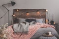 Grey and pastel pink blanket on grey bedding of fashionable bedroom with rustic design