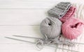 Grey and pink knitting wool and knitting needles on white wooden background. top view.copy space