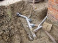 A grey plastic pipe construction in the ground next to a house