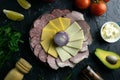 Grey plate with onion around the salami, ham, cheese and mozzarella. Tomato, souce, olives, lemon, olive oil with spice Royalty Free Stock Photo