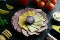 Grey plate with onion around the salami, ham, cheese and mozzarella. Tomato, souce, olives, lemon, olive oil with spice Royalty Free Stock Photo