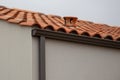 Grey rain gutters gray facade roof tiles on a home