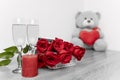 Grey and red view of champagne glasses, red roses bouquet and bear with red heart Royalty Free Stock Photo