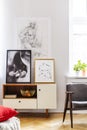 Grey retro armchair next to withe wooden cabinet