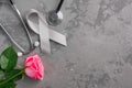 Grey ribbon, stethoscope and pink rose on a concrete background. Parkinson`s disease or brain cancer awareness concept