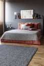 Grey rug in front of a king size bed with pillows and a painting Royalty Free Stock Photo