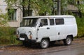 A grey Russian minivan is parked in the courtyard of a residential building