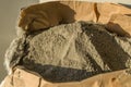 Grey sand-concrete dry mix in an open paper bag. Concrete dry powder for leveling walls and floors. Repair in the house Royalty Free Stock Photo