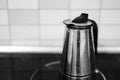 Grey-scale shot of a metal kettle on the stove in the kitchen