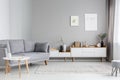 Grey settee near white cupboard in minimal living room interior Royalty Free Stock Photo