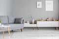 Grey settee near white cupboard in scandi living room interior w Royalty Free Stock Photo