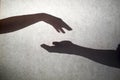 Grey shadows of hands reaching each other on the wall. Abstract blurred effect with space for text. Royalty Free Stock Photo