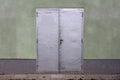 Grey sheet metal doors with small door handle mounted on house wall with stone tiles in front Royalty Free Stock Photo