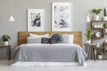 Grey sheets and cushions on wooden bed in bedroom interior with