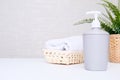 Grey soap dispenser, spa towel and green plan on white counter table inside a bright bathroom background with copy space Royalty Free Stock Photo