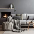 Grey sofa with woven blanket near fireplace. Scandinavian hygge home interior design of modern living room Royalty Free Stock Photo