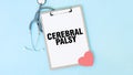 Grey stethoscope and paper plate with a sheet of white paper with text CEREBRAL PALSY light blue background. Medical concept