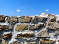 Grey ston wall detail under blue sky and small fluffy clouds Royalty Free Stock Photo