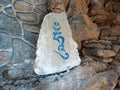 A grey stone with carved blue Hung buddhist mantra syllable.