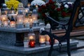 A grey tombstone filled with burning candles of various sizes and shapes.