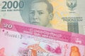 A grey two thousand Indonesian rupiah bank note paired with a pink and white twenty rupee bank note from Sri Lanka.