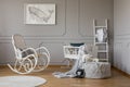 Grey whale on poster in stylish baby room interior with white wooden rocking chair and crib, copy space on empty wall Royalty Free Stock Photo