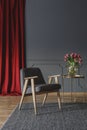 Grey wooden armchair on carpet next to gold table in living room