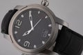Grey wristwatch with black dial, silver clockwise, and chronograph on black leather strap isolated on white background.