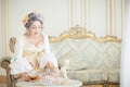 Greyhead woman in Rococo dress posing in front of pink background while drinking tea Royalty Free Stock Photo