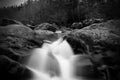 Greyscale Blurred Motion and Slow Shutter Waterscape Photography of a Water Fall over a Large Stones. Royalty Free Stock Photo