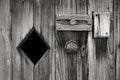 Greyscale closeup of a doorknob and lock on an old wooden door under the sunlight